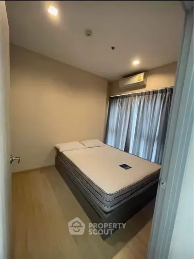 Cozy bedroom with modern design and ample natural light, featuring a comfortable bed and air conditioning.