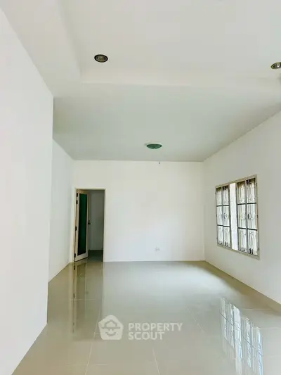 Spacious empty room with glossy tiled floor and large windows, perfect for customization.