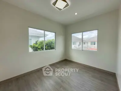 Bright empty room with large windows and modern flooring, perfect for customization.