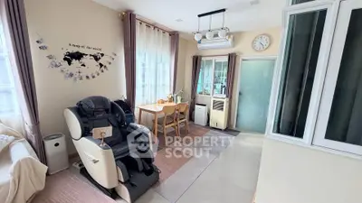 Cozy living room with massage chair and dining area, featuring world map wall art and natural light.