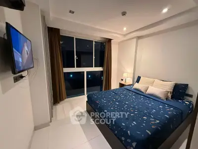Cozy modern bedroom with large window and wall-mounted TV, perfect for relaxation.