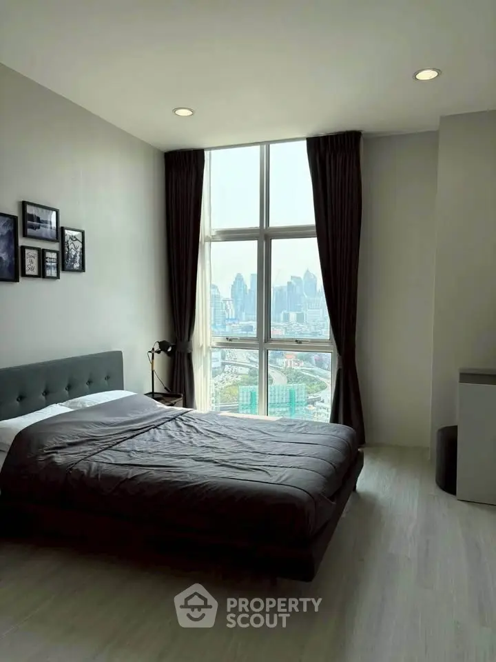 Modern bedroom with city view, featuring large window and stylish decor.