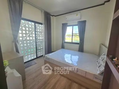 Modern bedroom with large window and balcony access, featuring stylish decor and natural light.