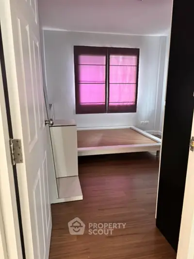 Spacious bedroom with wooden flooring and large window, perfect for natural light.