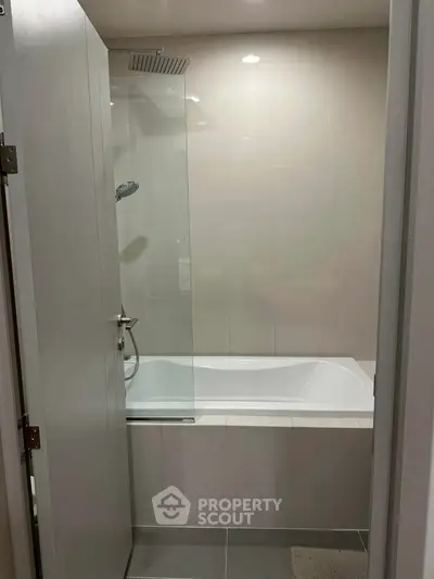 Modern bathroom with sleek bathtub and shower in a compact space.