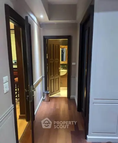 Elegant hallway leading to a cozy bathroom with wooden flooring and stylish decor.