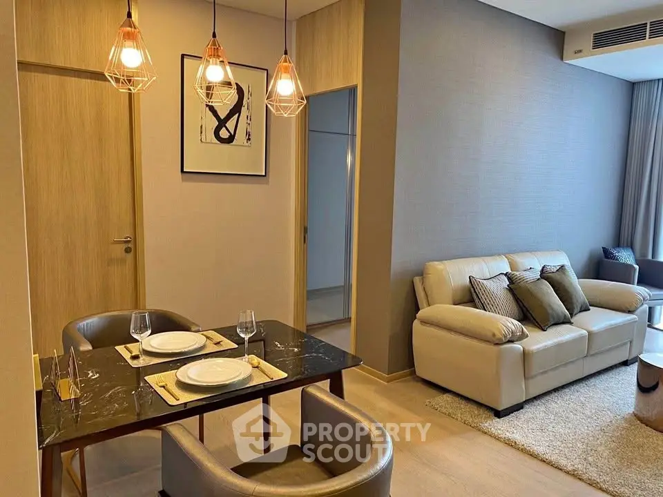 Modern living room with elegant dining area and cozy seating, featuring stylish lighting and contemporary decor.