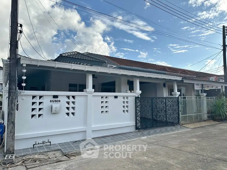 Charming single-story house with gated entrance and tiled roof in a serene neighborhood.