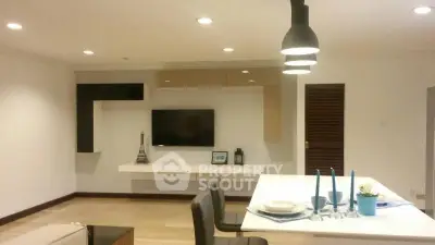 Modern living room with stylish decor and open layout, featuring a sleek TV setup and elegant dining area.