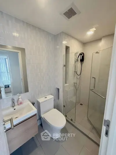 Modern bathroom with sleek fixtures and glass shower enclosure in a contemporary apartment.