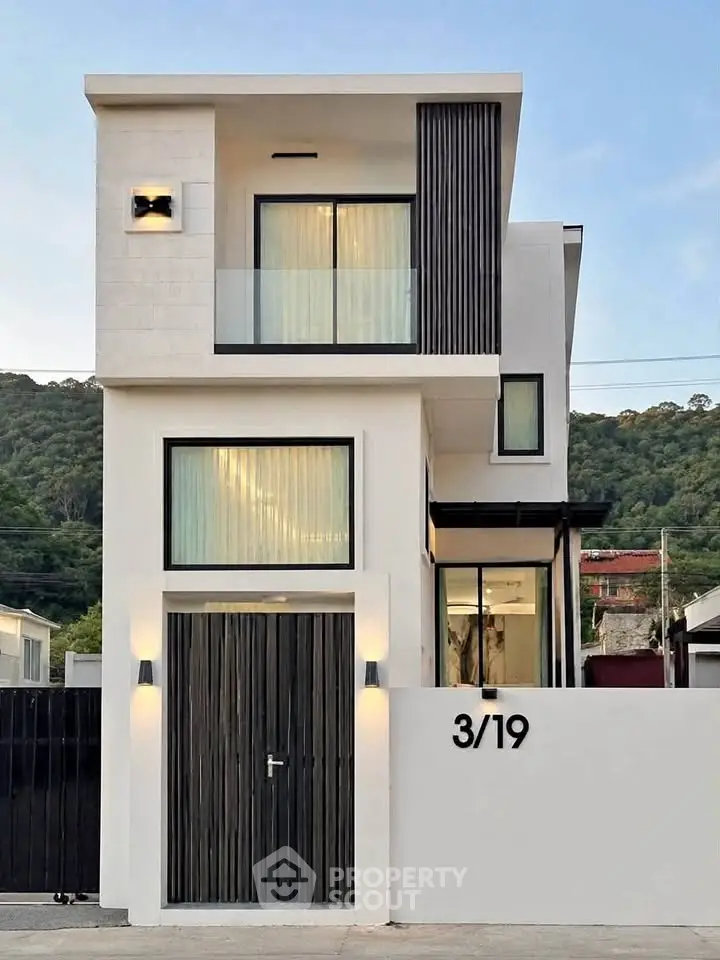 Modern two-story house with sleek design and large windows, set against a scenic mountain backdrop.