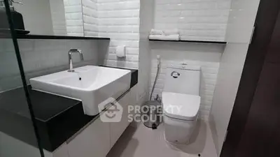 Modern bathroom with sleek white tiles and contemporary fixtures.