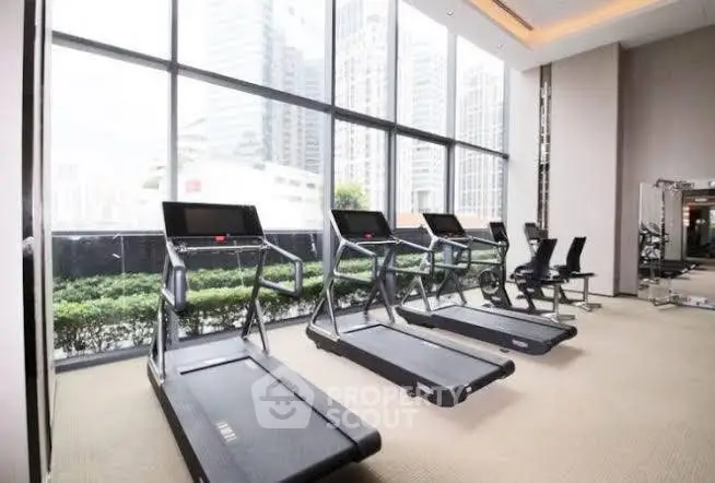 Modern gym with treadmills and city view in luxury apartment building