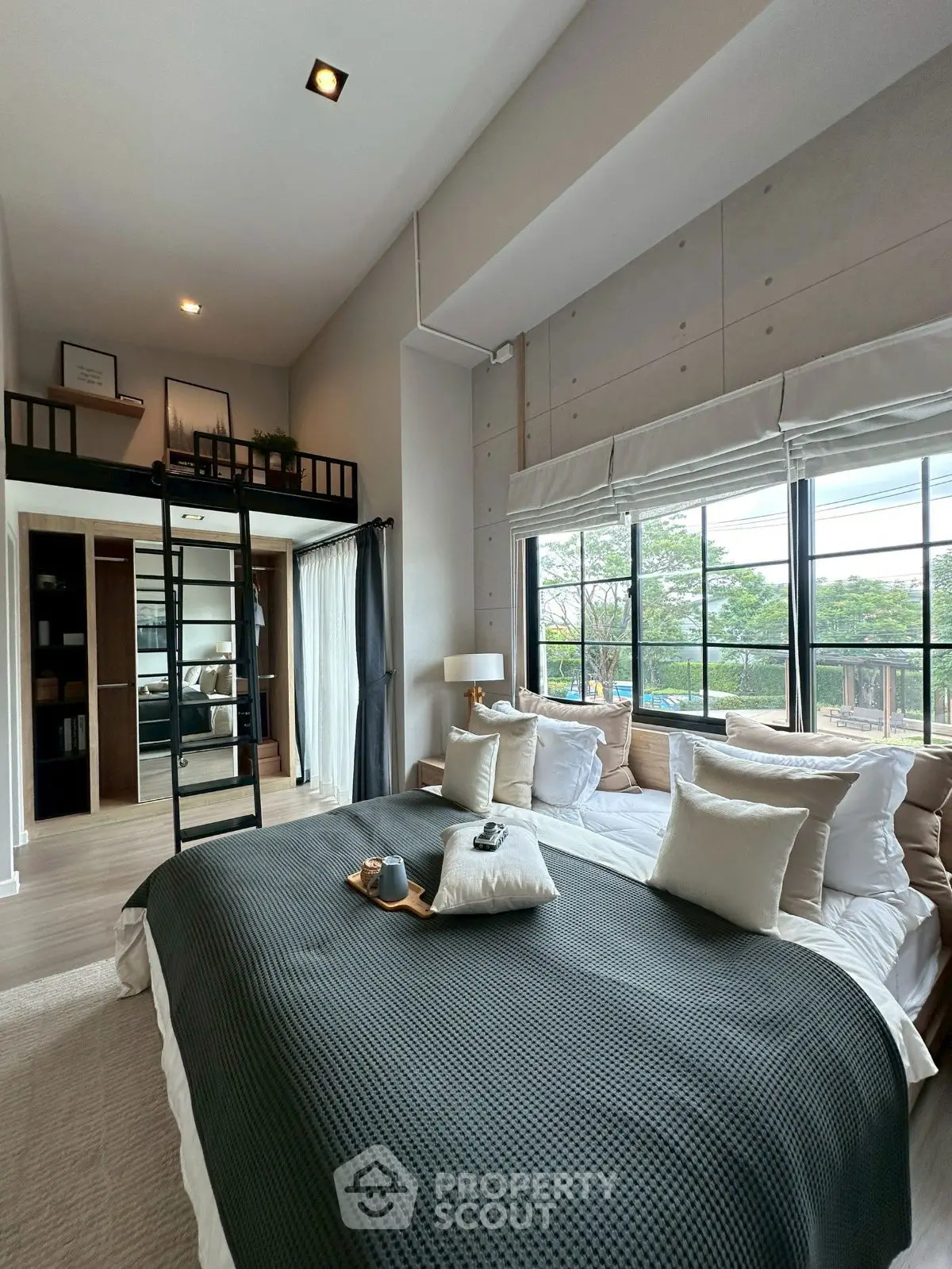 Modern bedroom with loft, large window, and stylish decor in a contemporary apartment.