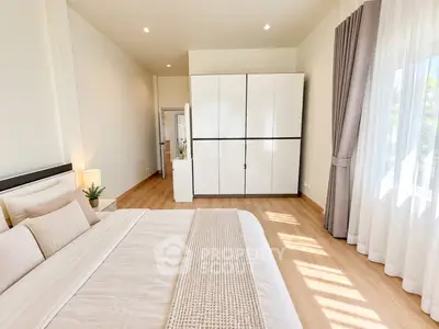 Spacious and bright bedroom with modern decor and large window for natural light.