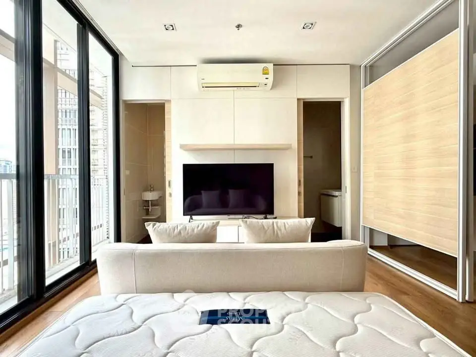 Modern living room with large windows and sleek furniture in a high-rise apartment.