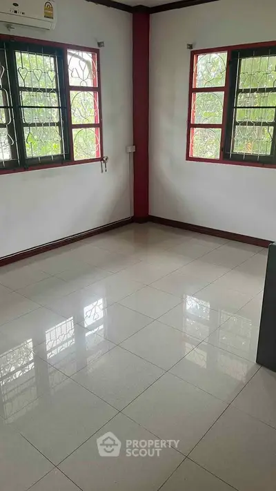 Spacious empty room with tiled flooring and large windows for natural light.