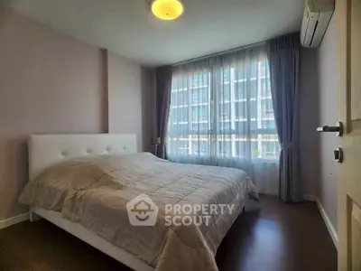 Spacious bedroom with large window and modern decor in a stylish apartment.