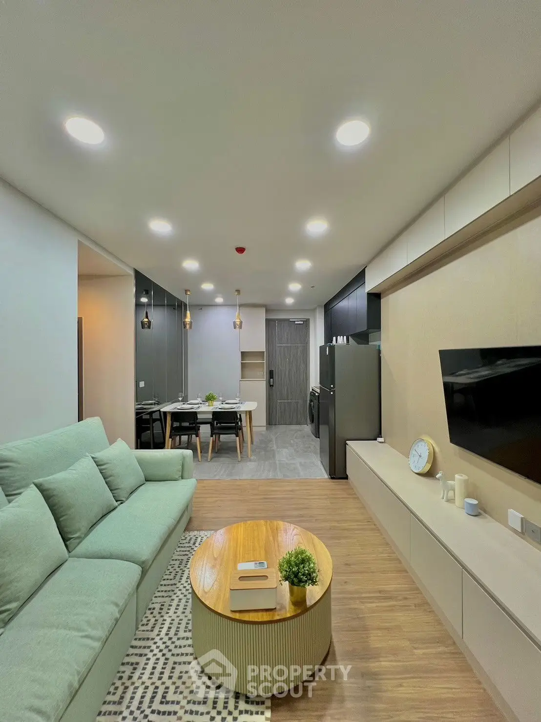 Modern living room with open kitchen, sleek furniture, and ambient lighting