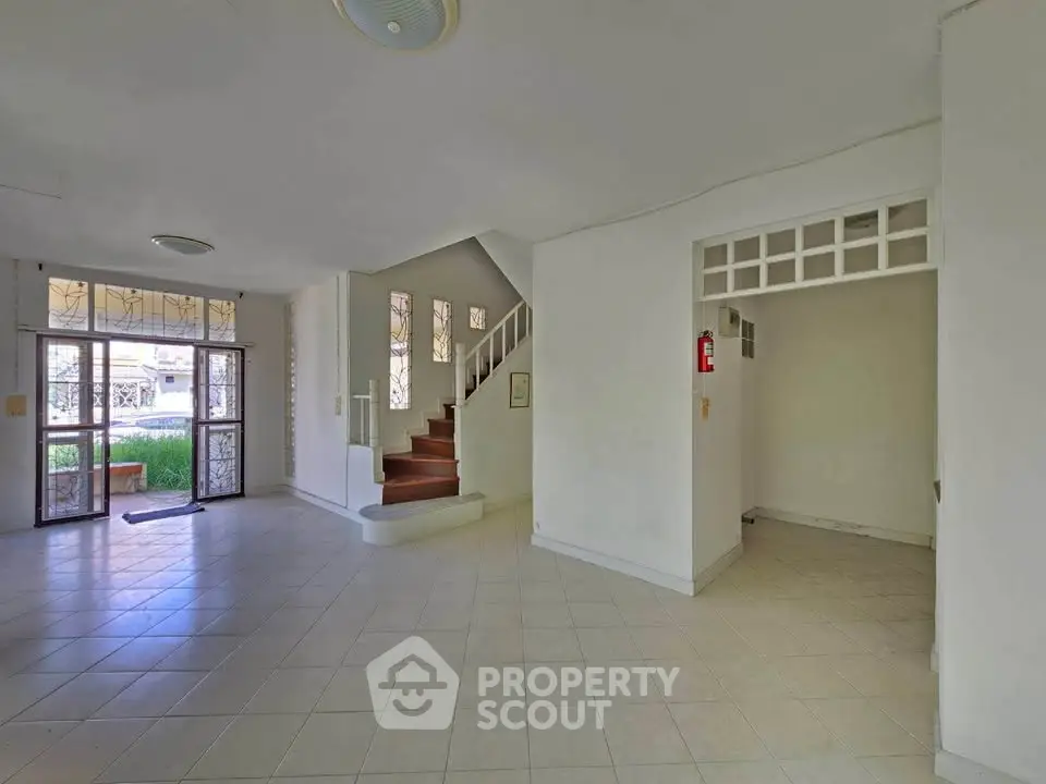 Spacious open-plan living area with tiled floors and staircase, ideal for modern family living.