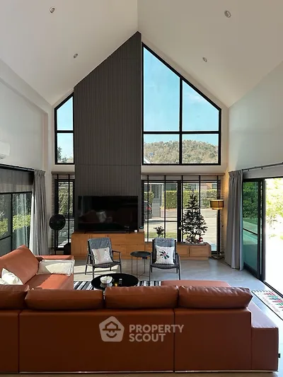 Spacious modern living room with high ceilings and large windows offering scenic views.