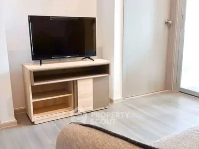 Modern living room with sleek TV stand and flat-screen TV, showcasing minimalist design and bright flooring.