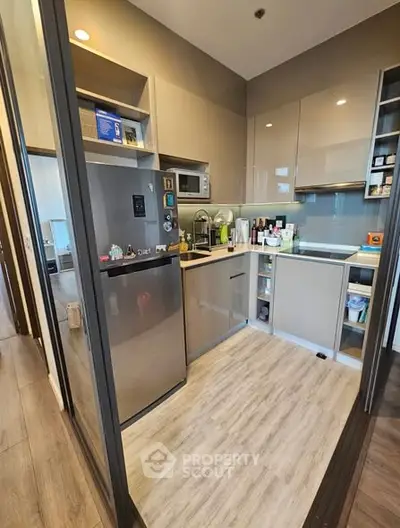 Modern compact kitchen with sleek cabinetry and stainless steel appliances in a stylish apartment.
