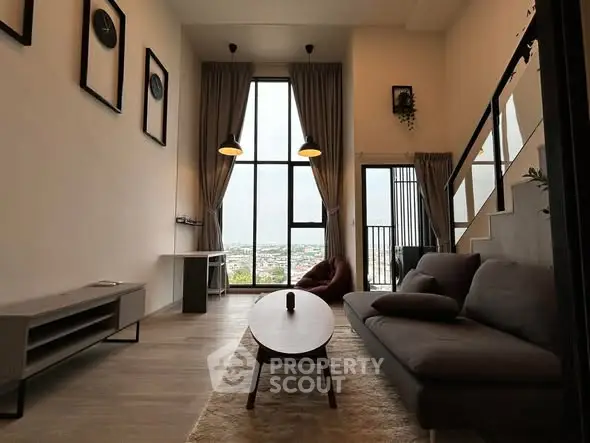 Modern living room with high ceilings and large windows offering stunning city views.