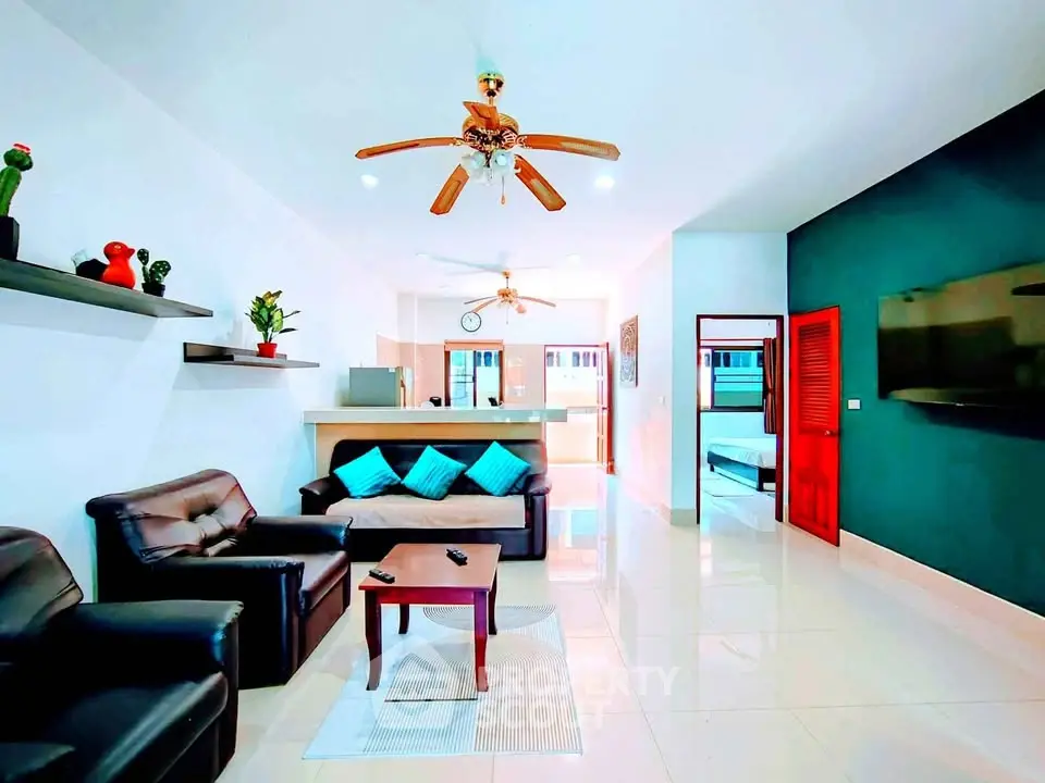 Spacious living room with modern decor and open layout, featuring comfortable seating and stylish ceiling fan.