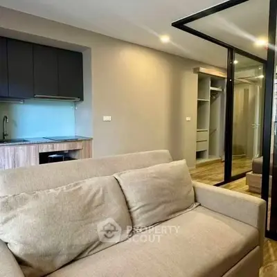 Modern living room with sleek kitchen and cozy sofa in open layout apartment.