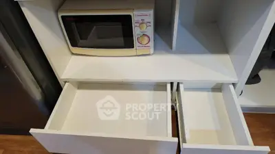 Modern kitchen with microwave and open drawers, showcasing efficient storage solutions.