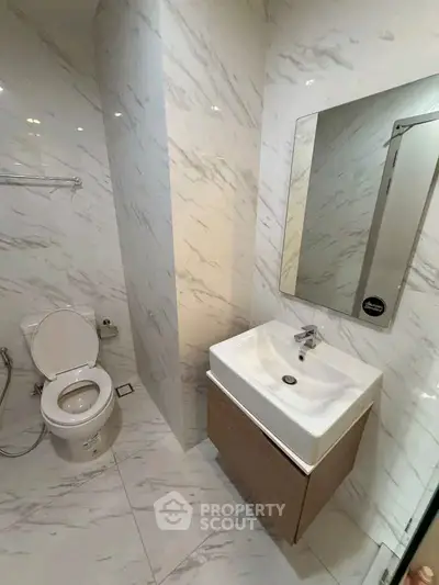 Modern bathroom with sleek white marble tiles and contemporary fixtures.