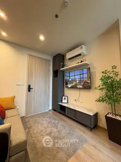 Cozy living room with modern decor, featuring a wall-mounted TV and air conditioning unit.