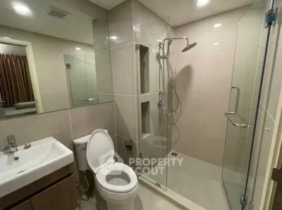 Modern bathroom with glass shower and sleek fixtures in a contemporary apartment.