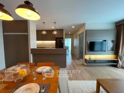 Modern open-plan living room with stylish kitchen and dining area, featuring elegant lighting and contemporary decor.