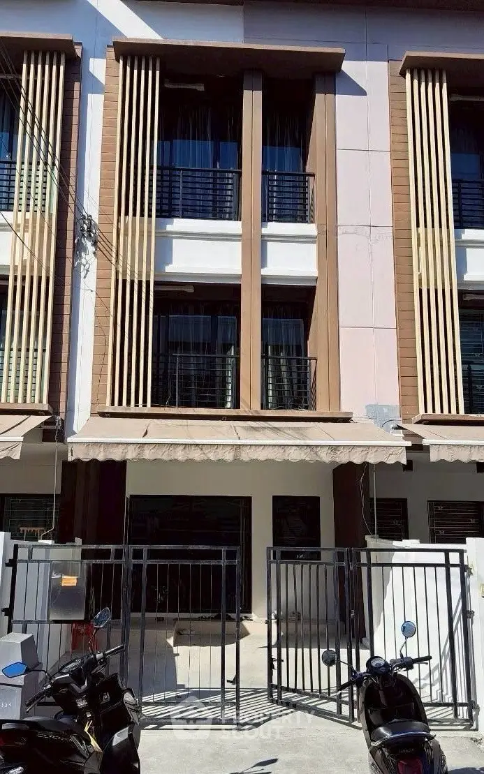 Modern townhouse exterior with gated entrance and vertical design elements.