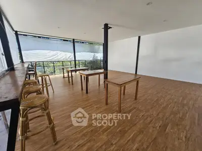 Spacious modern interior with wooden flooring and large windows, ideal for versatile use.