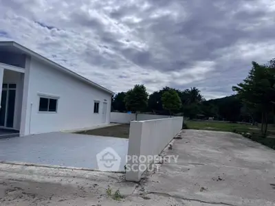 Modern single-story house with spacious driveway and lush greenery, perfect for serene living.