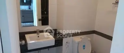 Modern bathroom with sleek fixtures and a view into the kitchen area.