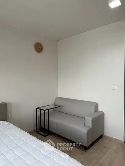 Cozy modern bedroom with a sleek gray sofa and minimalist decor, perfect for relaxation.