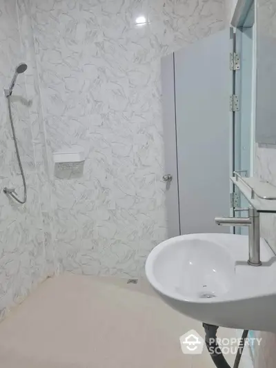 Modern minimalist bathroom with sleek fixtures and marble tile walls.