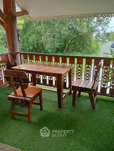 Charming wooden balcony with lush garden view, perfect for relaxation and outdoor dining.