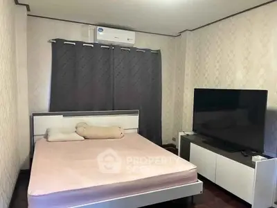 Cozy bedroom with modern decor and large TV, perfect for relaxation.