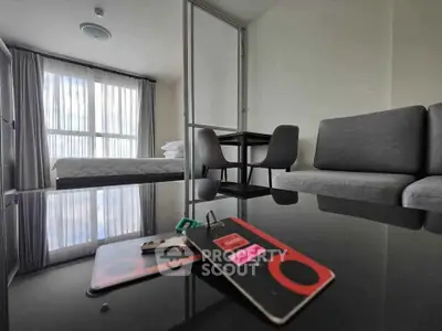 Modern studio apartment with sleek furniture and large window for natural light.