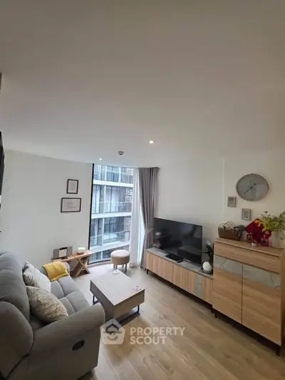 Modern living room with stylish decor and large window view in urban apartment.