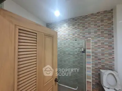 Modern bathroom with colorful tiled wall and wooden door
