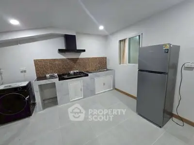 Modern kitchen with sleek appliances and open layout, featuring a gas stove and washing machine.