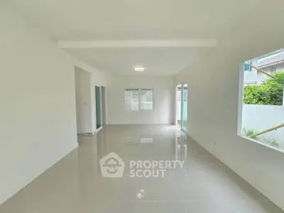 Spacious and bright living room with large windows and glossy tiled floors.