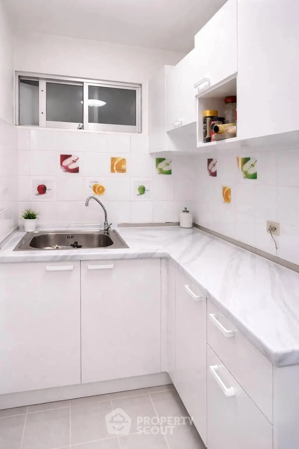 Modern white kitchen with sleek cabinets and colorful tile accents, featuring a stainless steel sink and ample counter space.