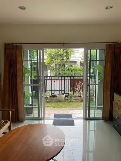 Charming living room with sliding glass doors opening to a lush garden view, perfect for relaxation.